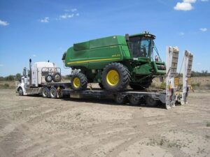 John Deere 9870 STS combine secured on a removable gooseneck trailer for long-distance agricultural transport