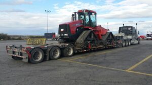 Red Case IH STX450 track tractor secured on a trailer with an oversize load sign for interstate hauling