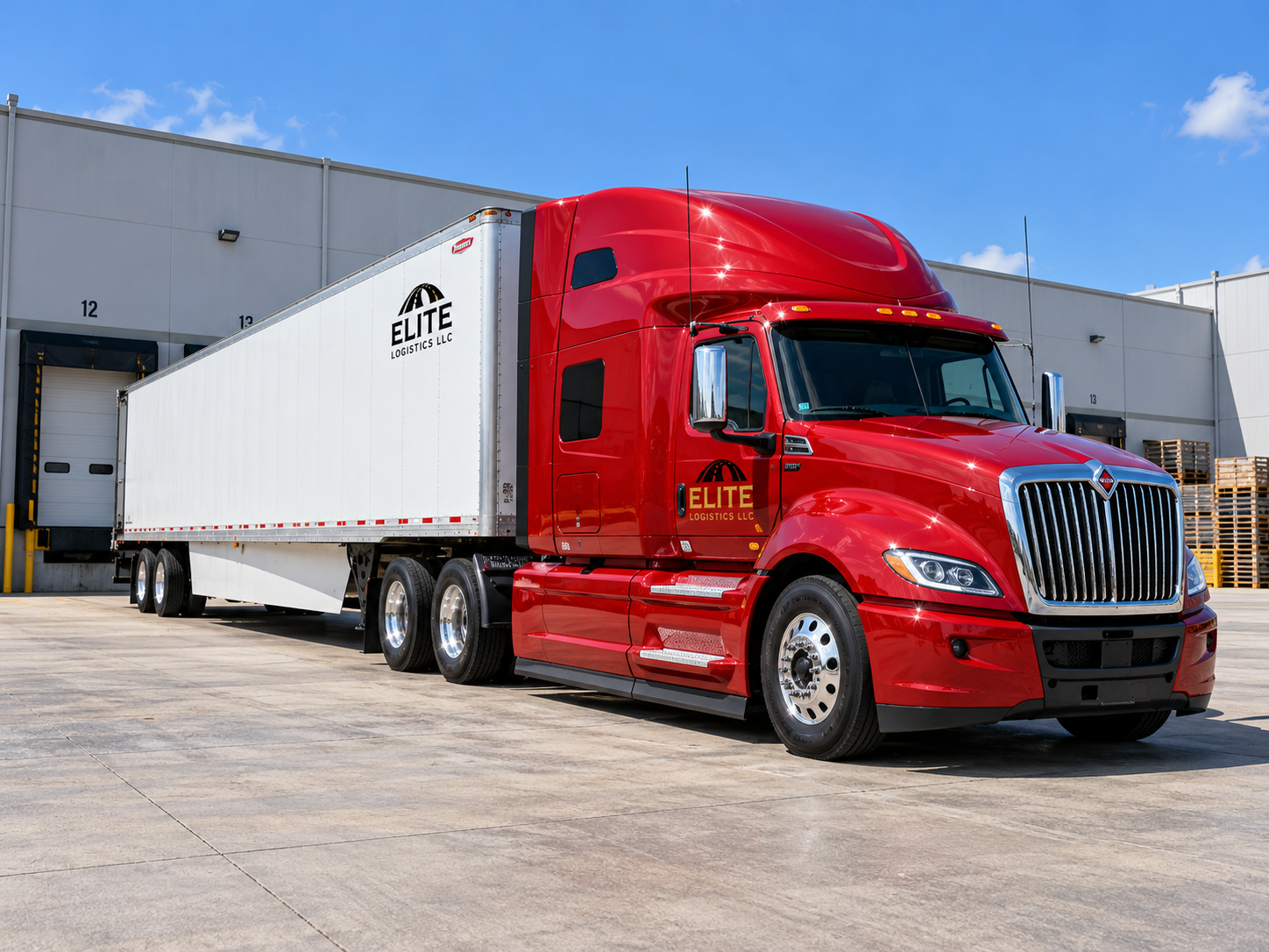 Red Elite Logistics semi truck with a white dry van trailer parked at warehouse loading docks.