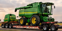 Green combine harvester with folded unloading auger secured on a lowboy trailer for oversize combine hauling