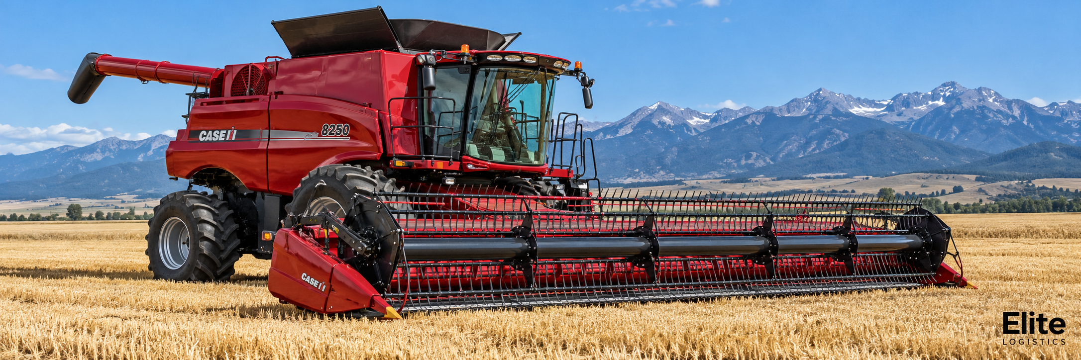 Red combine harvester with a wide grain header in a Montana field, representing Elite Logistics farm equipment hauling.